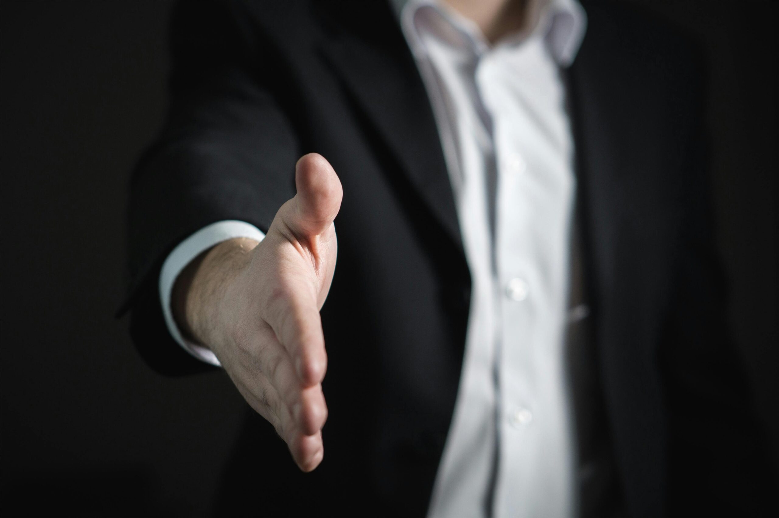 Two people shaking hands across a table symbolizing negotiation between borrower and lender