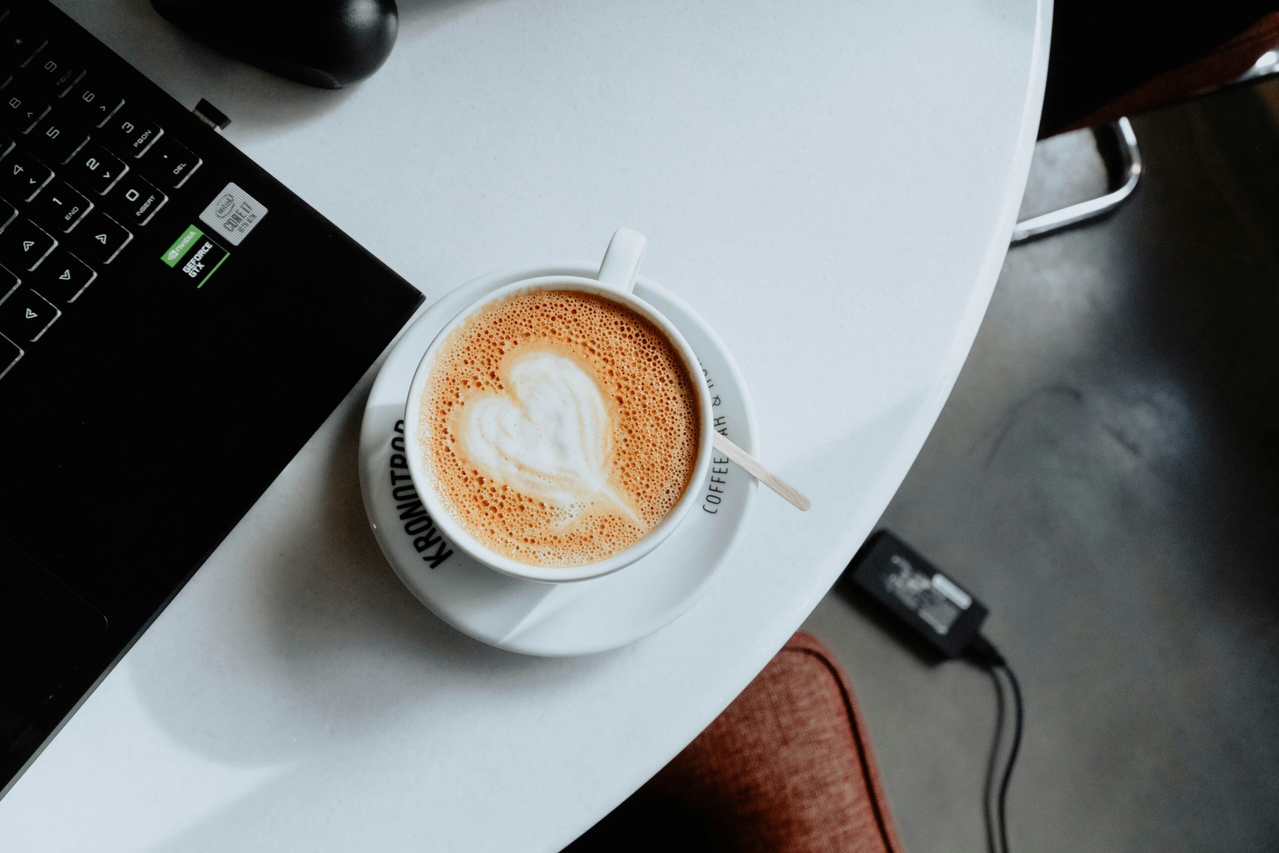 A steaming cup of coffee next to a laptop displaying loan calculations